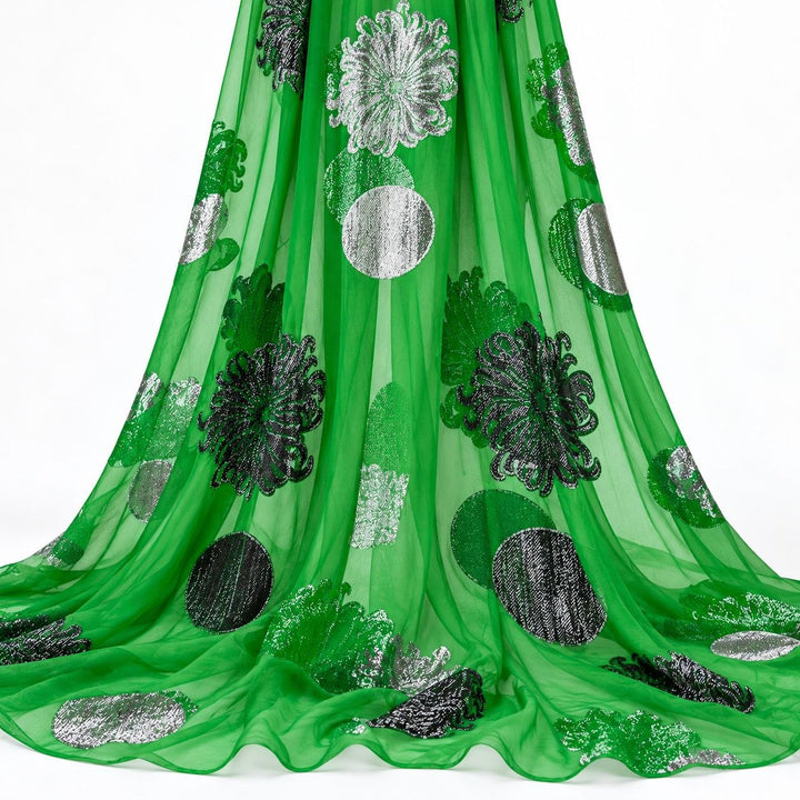Smaragdgrön lurex chiffonsilk med silverfärgade blommor och cirkelmotiv – hängande i mjuka veck på vit bakgrund (bild 2 av 3)