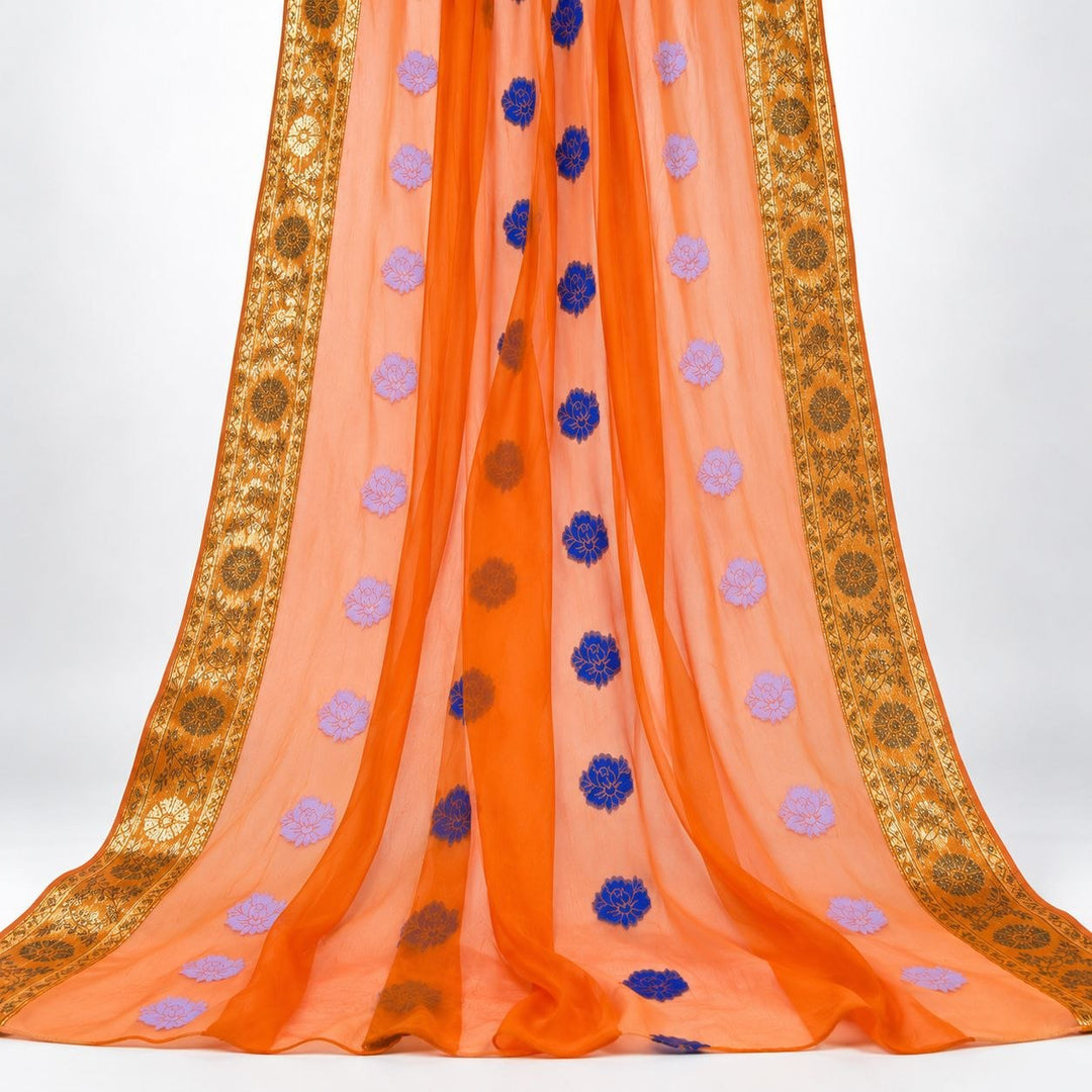 Orange lurex chiffonsilk med blommotiv – hängande i mjuka veck, guldborterna längs båda sidorna synliga (bild 2 av 3)