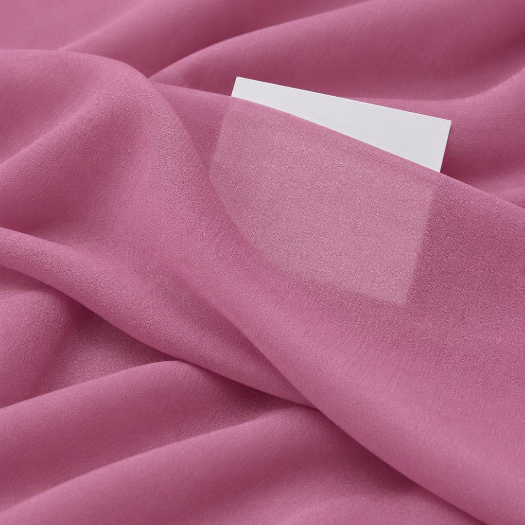 Dammigt rosa sidengeorgette – närbild med papper bakom tyget som visar att det bara är svagt genomskinligt (bild 3 av 3)