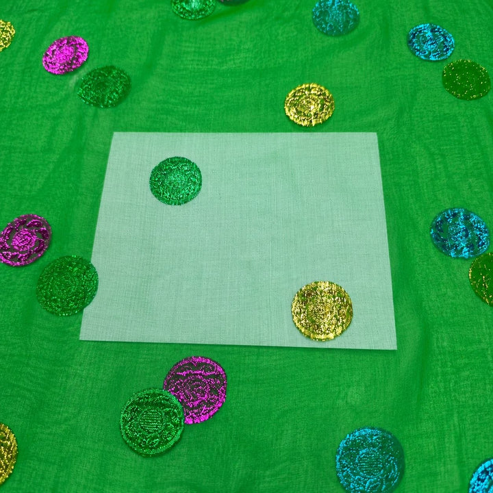 Grön lurex chiffonsilk – närbild på de flerfärgade prickarna och tygets genomskinlighet (bild 3 av 3)